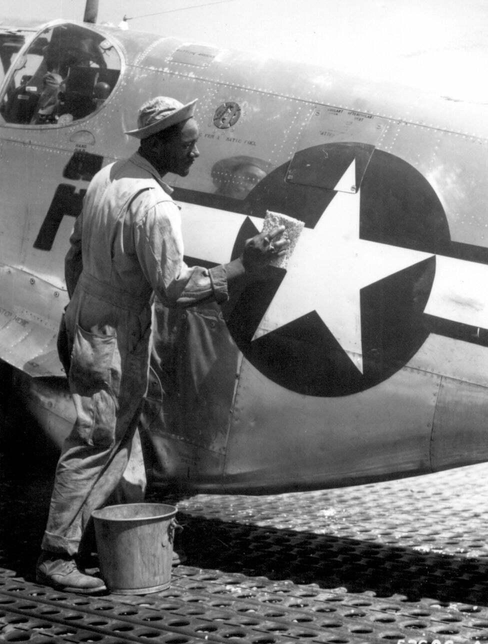 Tuskegee Airman cleaning aircraft insignia
