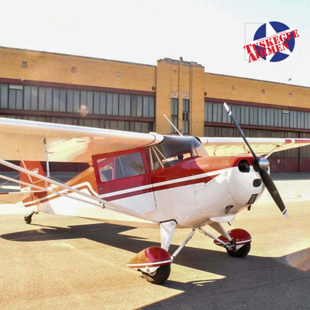 A vintage War Bird aircraft parked on the tarmac in front of the hangar at Coleman A. Young International Airport