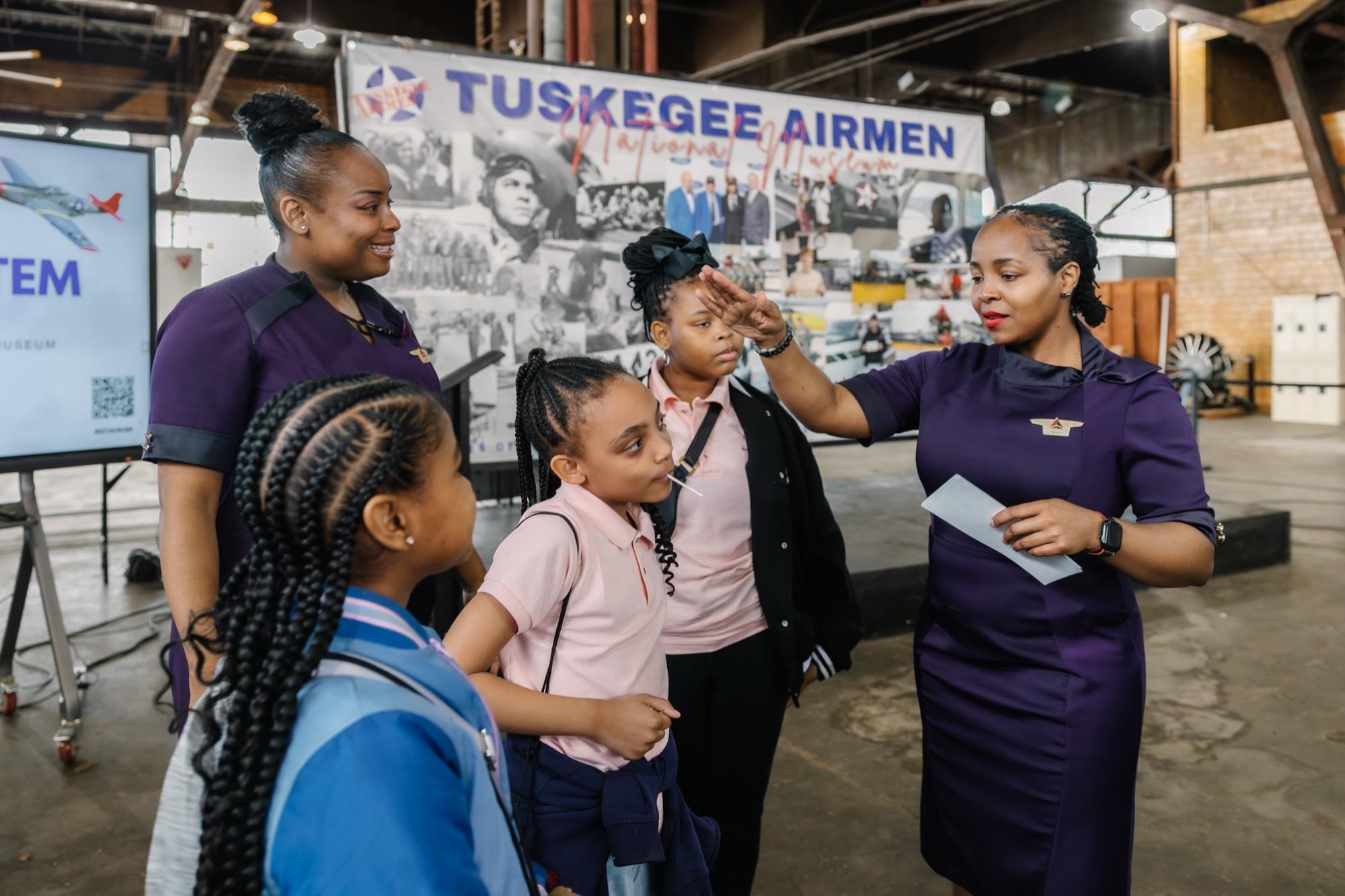 Museum staff giving students a tour in front of the Tuskegee Airmen exhibit